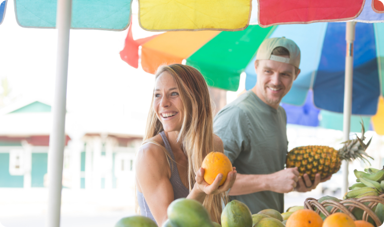 couple smiling looking at fruit at a market